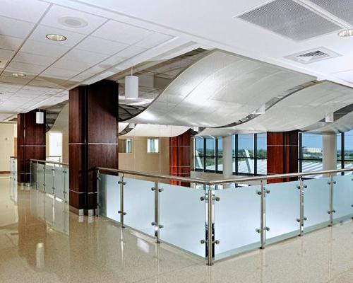 Interior photo from inside St John Broken Arrow. Wave like structures hang form the ceiling. Frosted glass and metal railing surround the overlook.